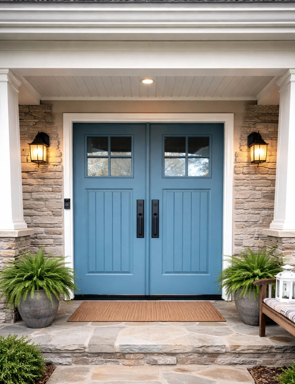 Blue double doors with glass panels on a stone facade, flanked by two lights and plants.