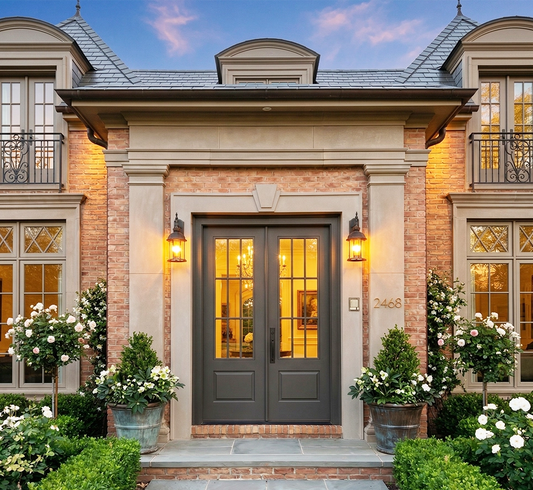 Elegant house entrance with a dark gray door, surrounded by decorative plants and flowers.